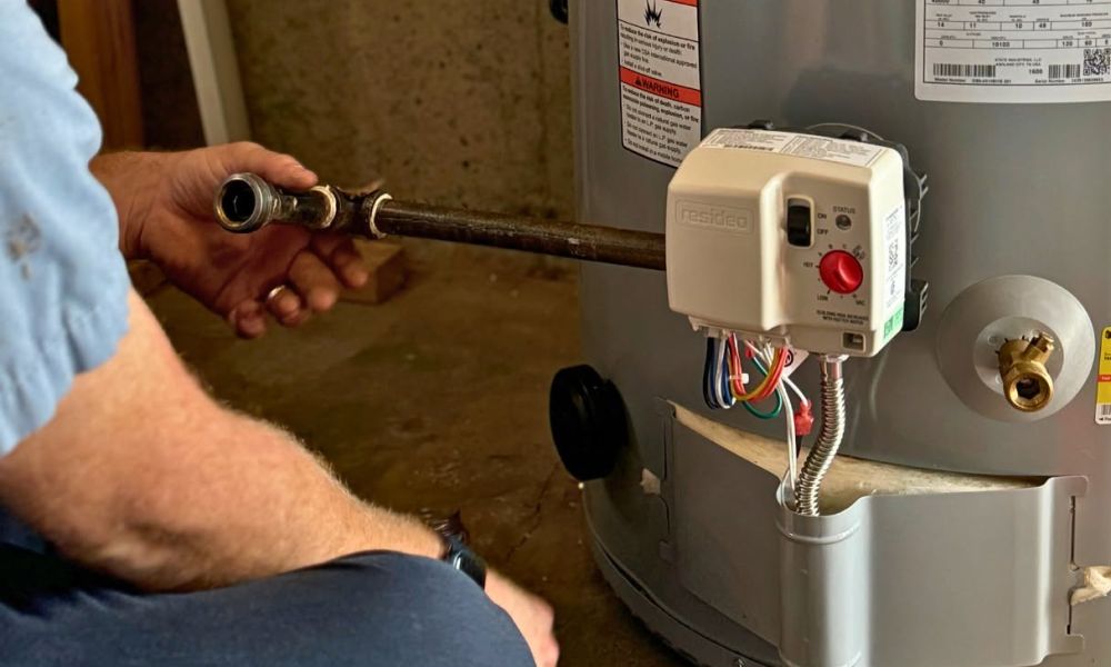 Technician working on water heater installation, adjusting a pipe connection for efficient home heating.