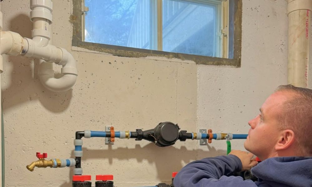 Person inspecting basement water filtration system with exposed pipes.