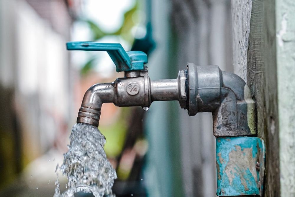 Outdoor water faucet with strong flow, highlighting water conservation and plumbing efficiency.