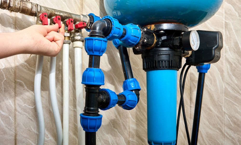 Person adjusting water filtration system valves, featuring blue and red components, ensuring efficient plumbing maintenance.