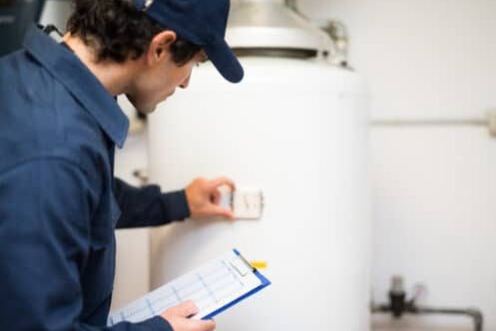 Technician inspecting water heater with clipboard in hand.