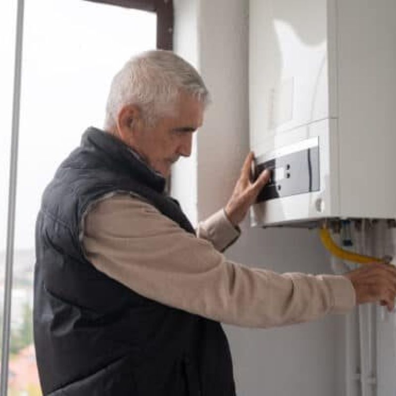 Man adjusting home boiler system for heating efficiency.